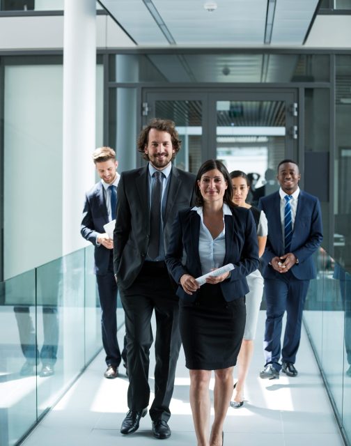 Portrait of businesswoman walking with colleagues in office